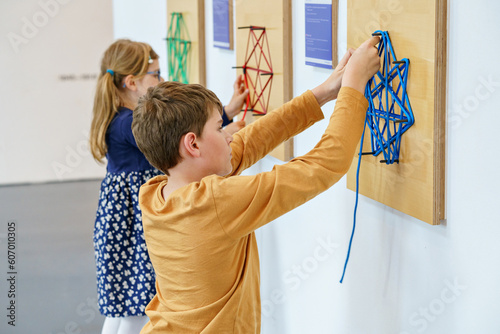 Two little children playing logical games indoor. Boy and little girl having fun with building and creating geometric figures. with strings in child museum for maths