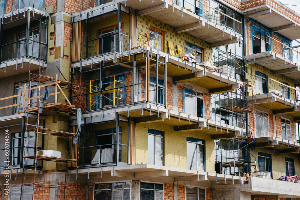 Building facade under renovation works with construction scaffolding frame. Wall insulation with styrofoam sheets for energy efficient home Building facade under renovation works with construction scaffolding frame. Wall insulation with styrofoam sheets for energy efficient home