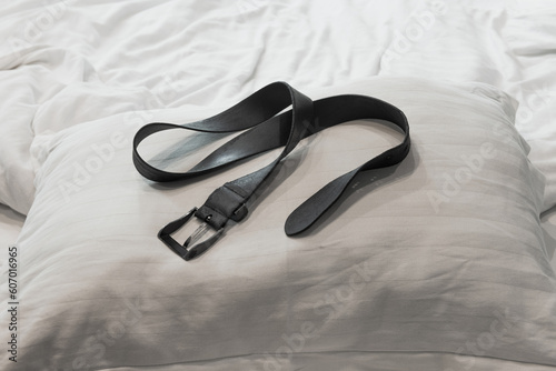 Leather belt on pillow prepared for discipline spanking. Domestic discipline, corporal punishment, spanking, sex role play, fetish concept. 