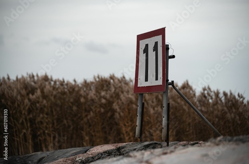 Fototapeta Naklejka Na Ścianę i Meble -  Sign saying 11 near the shore on a cloudy day.