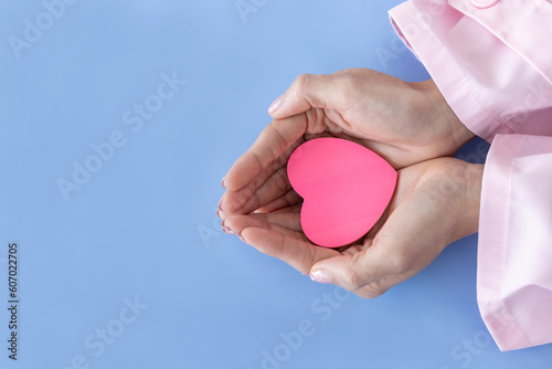Heart in Doctor's hands on blue background. A Doctor's hand protecting and reassures patient.Healthcare and hospital medical. Organ donation,charity,cardiologist,heart care .Valentine day.copy space..