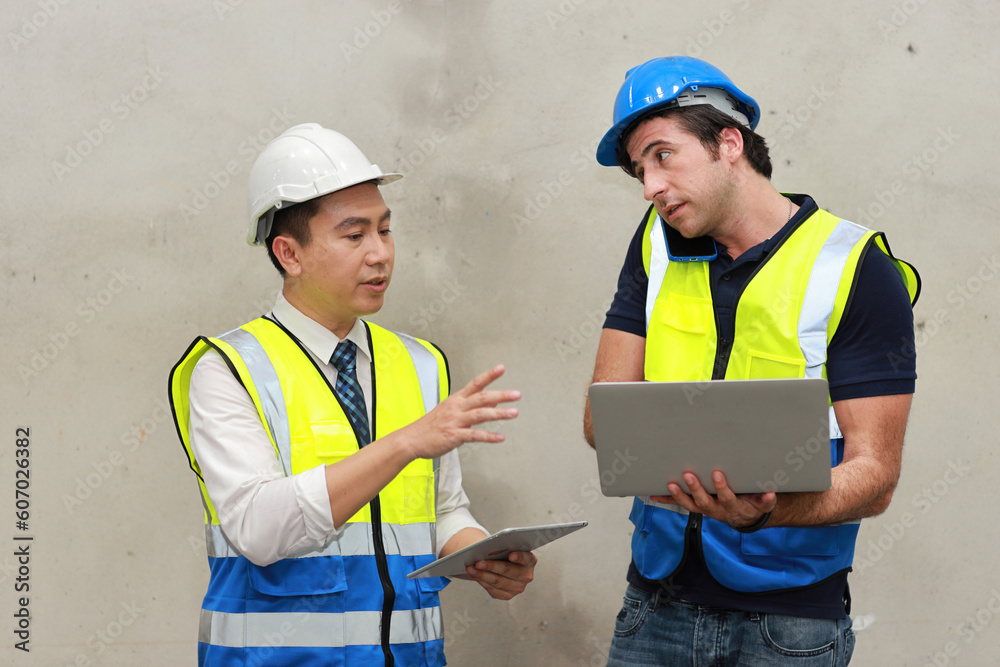 Architect or engineering men and worker standing and checking large warehouse with tablet. Multiethnic two business manager controlling work at warehouse industry building. Architect or engineering men and worker standing and checking large warehouse with tablet. Multiethnic two business manager controlling work at warehouse industry building.