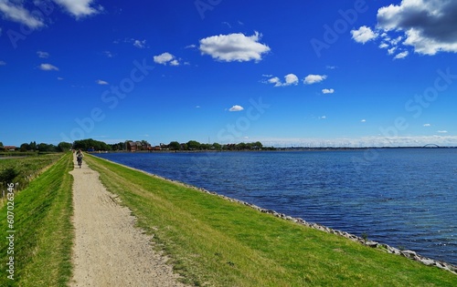 Image of a road with the Baltic Sea on the left and people riding bicycles in Fehmarn  Germany