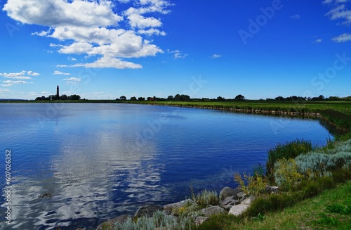Image of a water surface with grass on the coast and a beautiful sky above © Stephan Hickisch/Wirestock Creators
