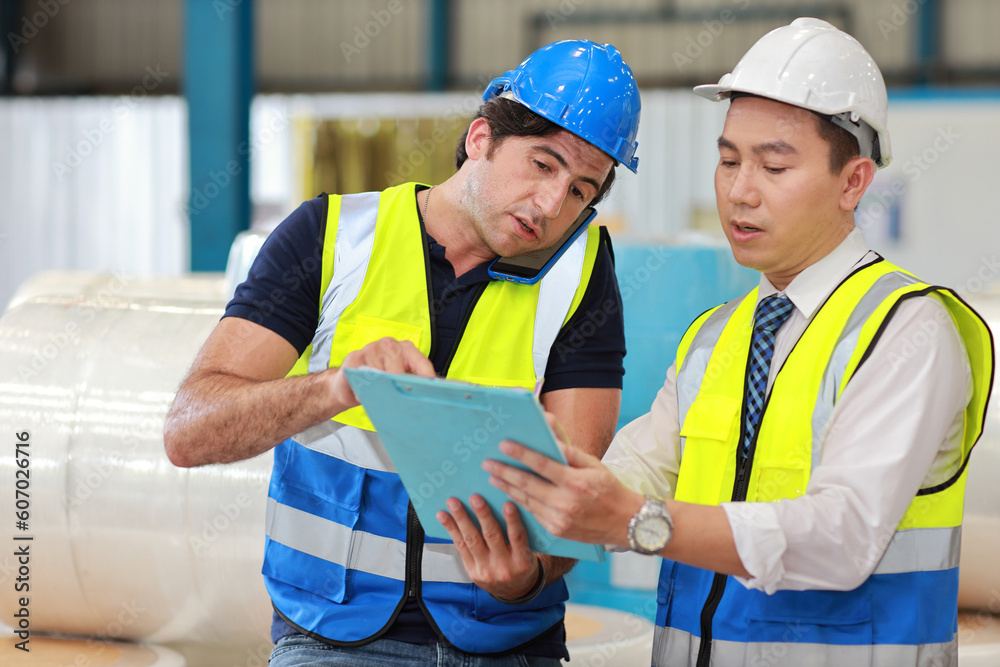 Architect or engineering man and worker sitting and checking large warehouse with computer. Multiethnic two business manager pointing and looking in future with warehouse building background. Architect or engineering man and worker sitting and checking large warehouse with computer. Multiethnic two business manager pointing and looking in future with warehouse building background.