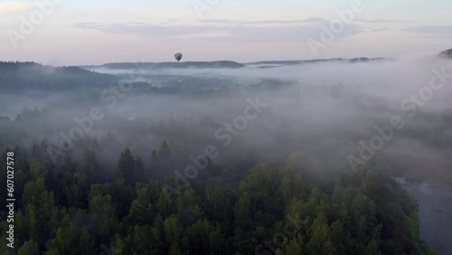 Done flight above valley filled with fog towards a hot air balloon. photo