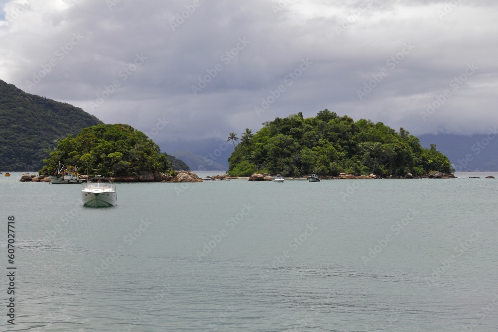 White boat against green islands in Ilha Grande, Brazil under the cloudy sky