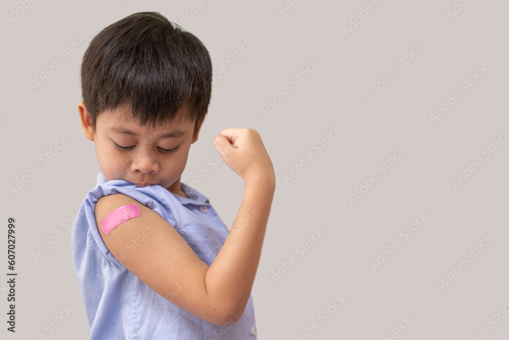 Portrait of happy smile vaccinated little asian kid boy children ages 5 to 11 years old posing show arm with medical plaster after Injection vaccine Covid-19 protection.coronavirus vaccination kid Portrait of happy smile vaccinated little asian kid boy children ages 5 to 11 years old posing show arm with medical plaster after Injection vaccine Covid-19 protection.coronavirus vaccination kid