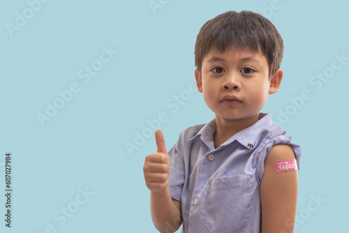 Portrait of happy smile vaccinated little asian kid boy children ages 5 to 11 years old posing show arm with medical plaster after Injection vaccine Covid-19 protection.coronavirus vaccination kid