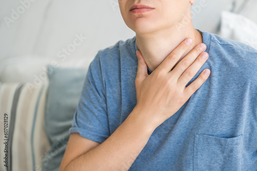 Fotografia Sore throat and cough, man with pain in neck at home