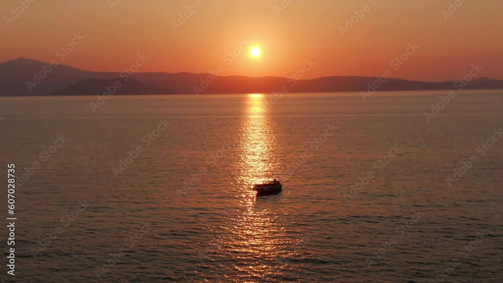 Aerial drone arc shot of small Fishermans boat with sunset and mountains in background Aerial drone arc shot of small Fishermans boat with sunset and mountains in background