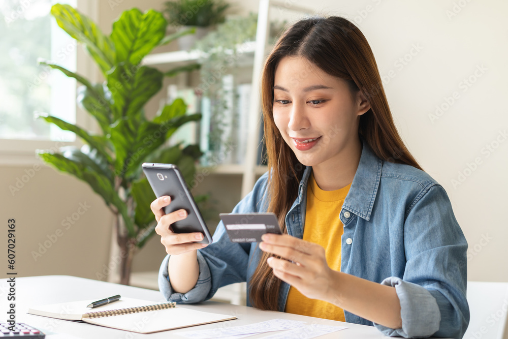 Online internet banking, smile asian young woman hand holding credit card to payment spending, using mobile phone scan qr code to transfer or pay money without cash at home. Technology of financial. Online internet banking, smile asian young woman hand holding credit card to payment spending, using mobile phone scan qr code to transfer or pay money without cash at home. Technology of financial.