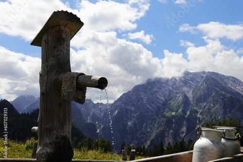 Closeup shot of a wooden water fountain with mountains in the background in Bavaria Germany