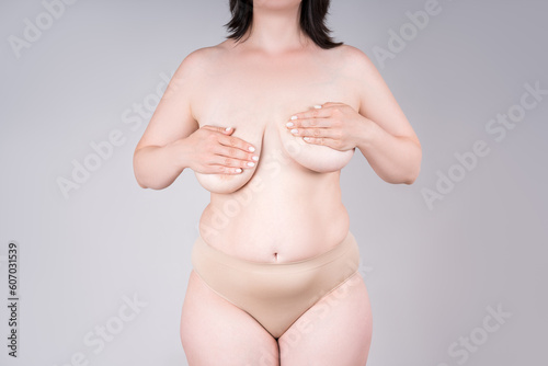 Women's breasts of different sizes on grey background, plastic surgery and aesthetic medicine concept