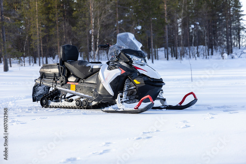 Snowmobile on a frozen lake with pine tree forest in the background