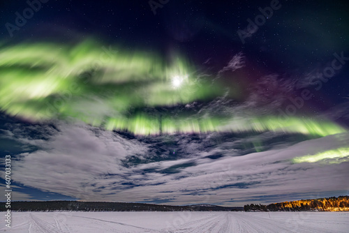 Circular green Northern lights (aurora borealis) with moon above Ounasjärvi lake in Hetta, Lapland, Finland