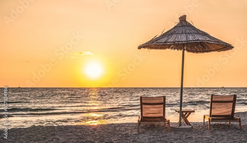 Fototapeta Naklejka Na Ścianę i Meble -  Sunbeds and parasols on beach in Sarande, Albania during sunset afternoon