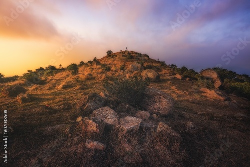 Hill with dry grass over a background of colorful clouds during a sunset