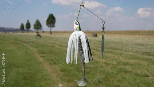 white Bass Jig head with spinnerbait for Fishing bass fish dangling in the air off of a Rod, at a ready to catch a fish. photo