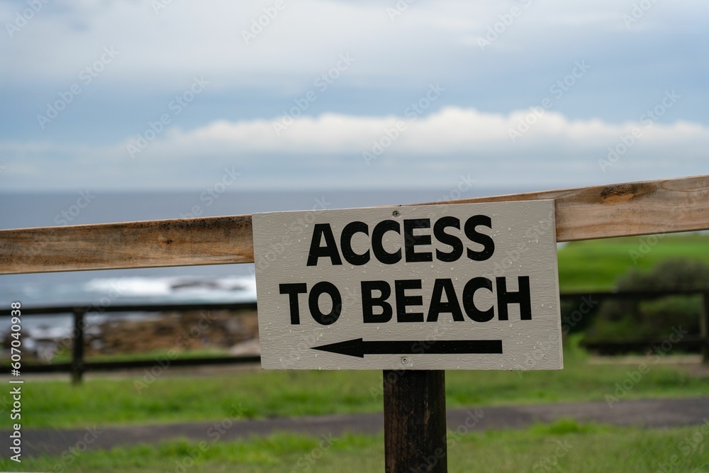 Closeup shot of access to beach sign pointing the way