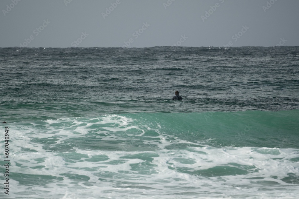 Closeup shot of a surfer trying to catch a wave at sunset