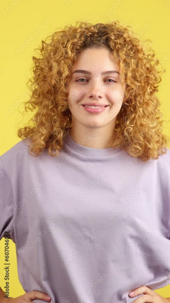 Smiley woman looking at camera standing, yellow background