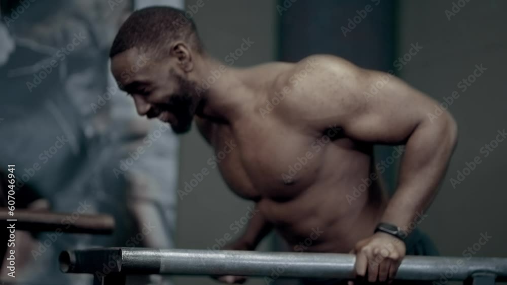 Athletic African American man smiling while warming up for dips Athletic African American man smiling while warming up for dips