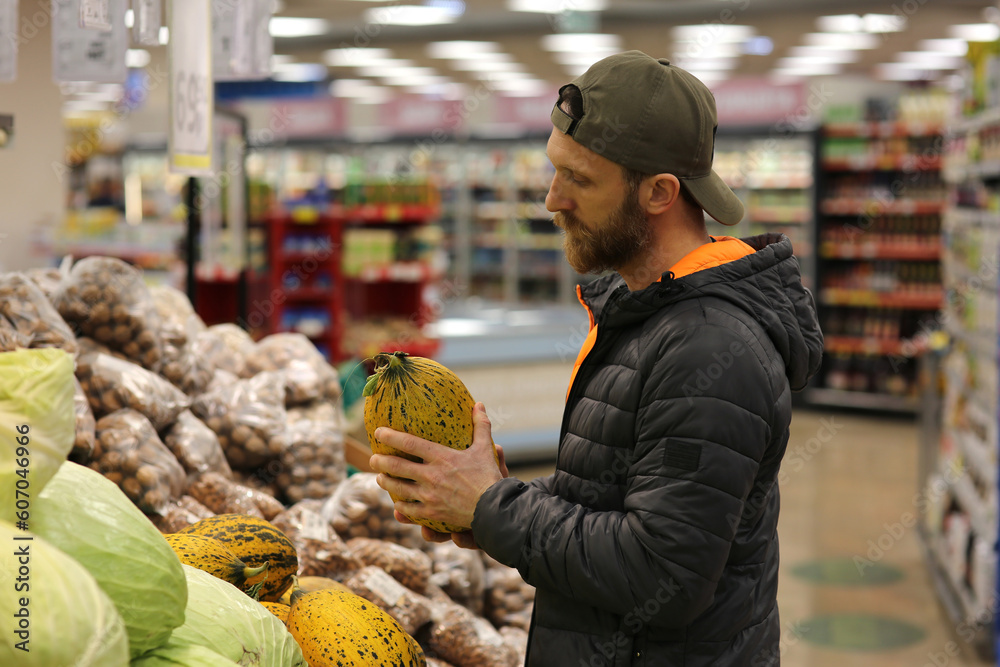 A bearded Caucasian man customer is interested in melons at the grocery store, supermarket. Copy space for text, advertising, message, logo