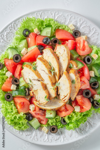 Healthy and classic Caesar salad with chicken, lettuce and tomatoes.