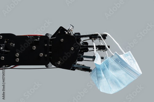 Robotic hand with medical face mask. Concept of AI in medicine.
