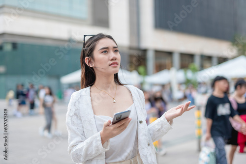 A young asian woman looking lost while looking for landmarks in the city. Confused with the map on her cellphone. A lady with no sense of direction or unfamiliar with the place. photo