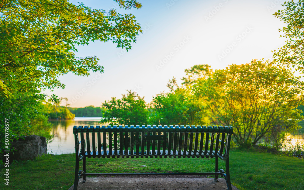 Bench in the park at sunset. Tranquil woodland landscape over Olney Pond at Lincoln Woods State Park Beach in Providence, Rhode Island
