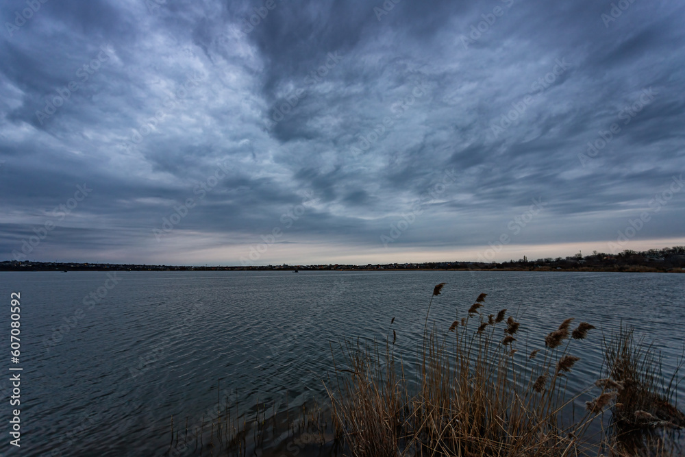 Late evening at the lake. Overcast and cloudy with tree branches in the foreground