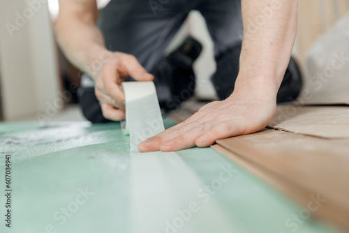 Professional builder use spreads underlayment for laying laminate flooring in white room