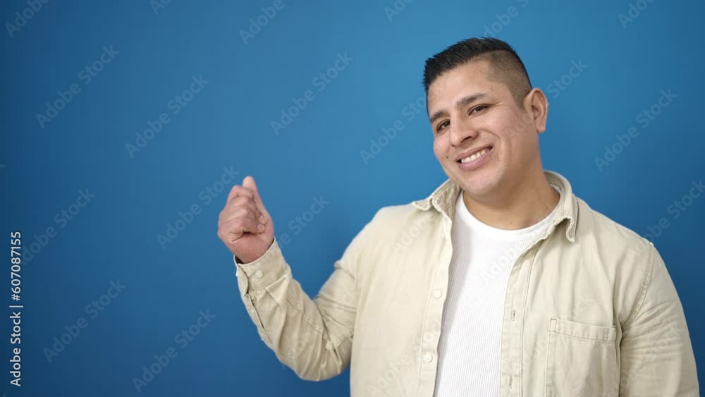 Young hispanic man smiling confident pointing to the side over isolated blue background Young hispanic man smiling confident pointing to the side over isolated blue background