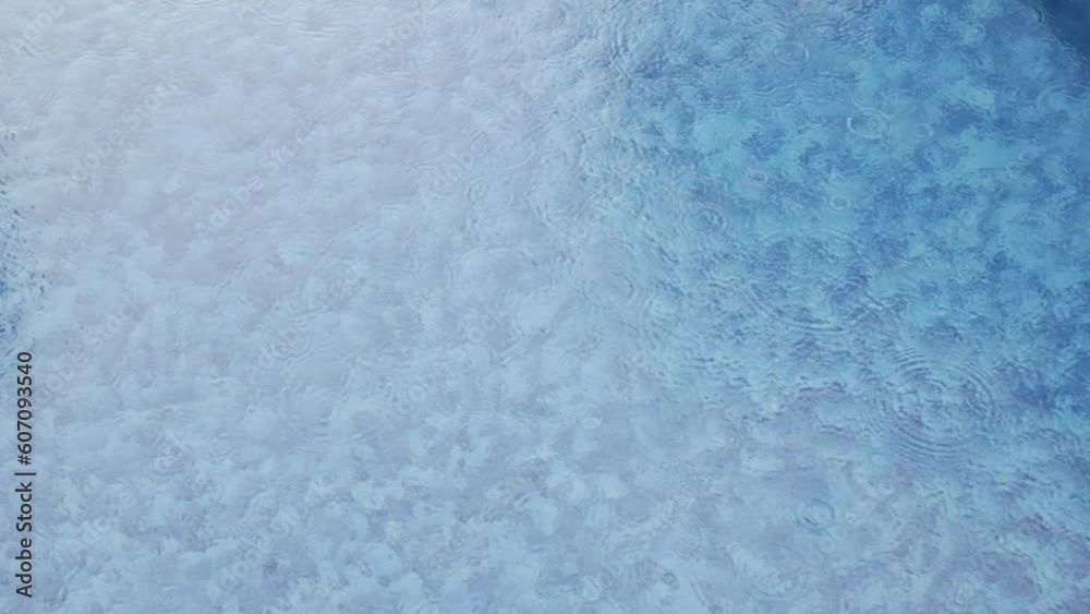 Rain droplets drops falling onto the surface of a swimming pool, Close up rain drop splash into the pool. Rainy mood weather forecast nature background Rain droplets drops falling onto the surface of a swimming pool, Close up rain drop splash into the pool. Rainy mood weather forecast nature background