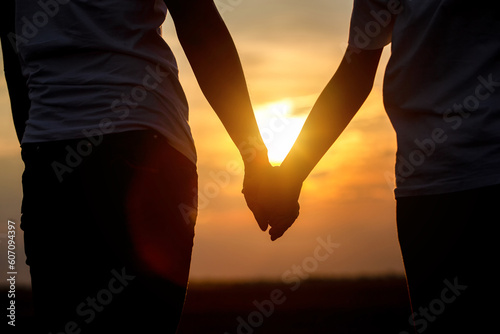 Silhouette of young love couple holding hands on sunset background. Freedom lifestyle romantic