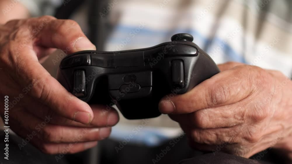 close-up in the hands of an old man a joystick from a game console. an elderly man spends his leisure time playing games on a game console. outdoor activities and hobbies of an old man close-up in the hands of an old man a joystick from a game console. an elderly man spends his leisure time playing games on a game console. outdoor activities and hobbies of an old man