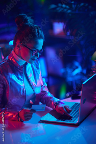 trendy woman in glasses with credit card using laptop
