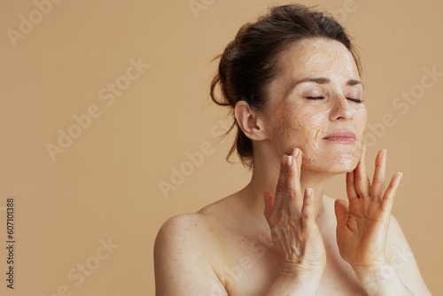 modern woman with face scrub against beige background