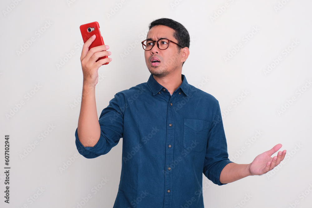 Adult Asian man searching for phone signal with confused expression Adult Asian man searching for phone signal with confused expression