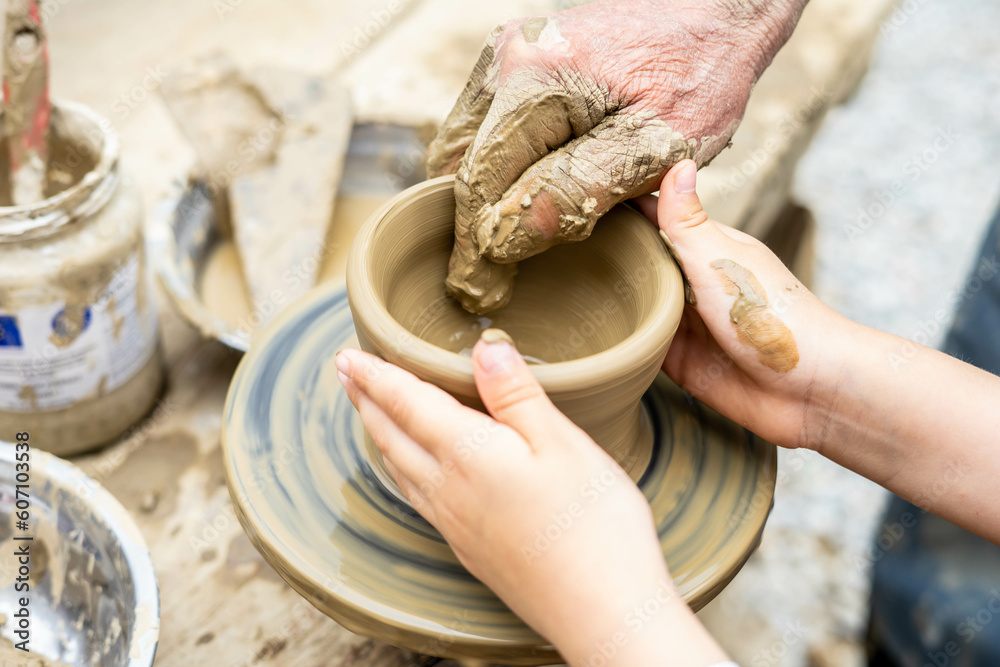 Child learning pottery from an old potter. Passing traditions  on trough generations. Handicraft