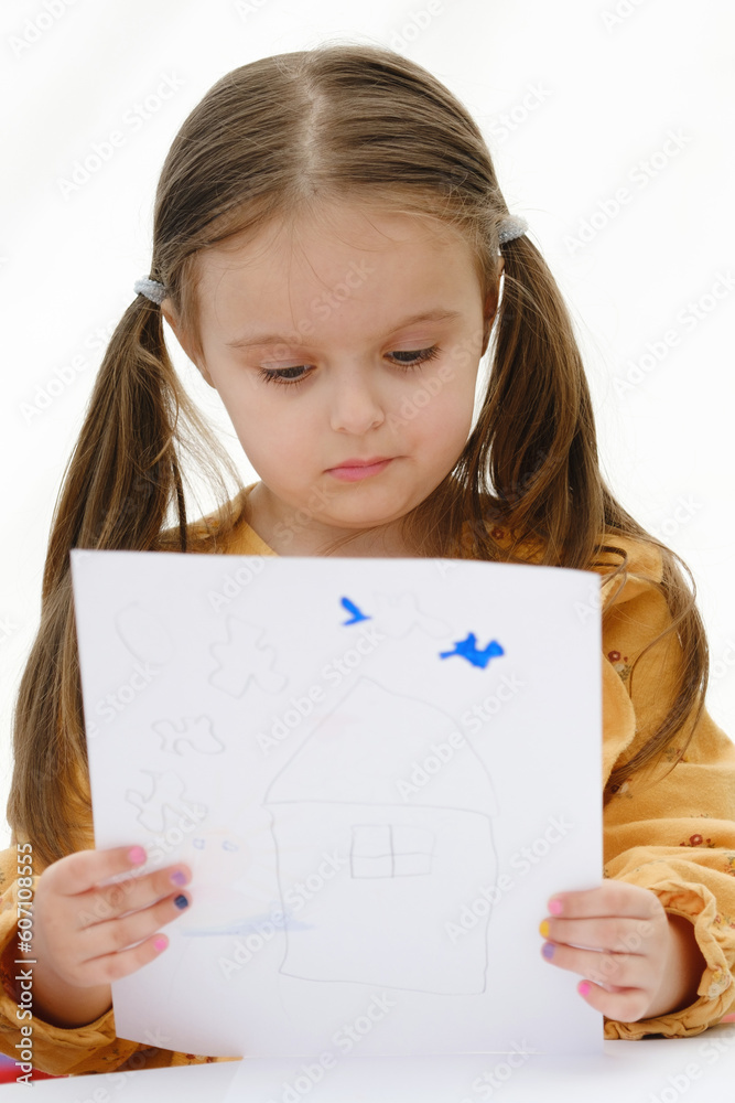 A preschooler girl is looking at a drawing she has drawn. A preschooler girl is looking at a drawing she has drawn.