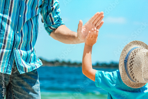 A happy dad holds the hand of a child by the greek sea in nature