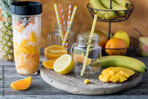 A rustic wooden board topped with everything to make a mango citrus smoothie.