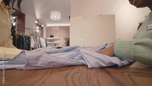 Cropped shot of unrecognizable female customer returning shirt to clothes store, examining quality of fabric at counter with shop clerk