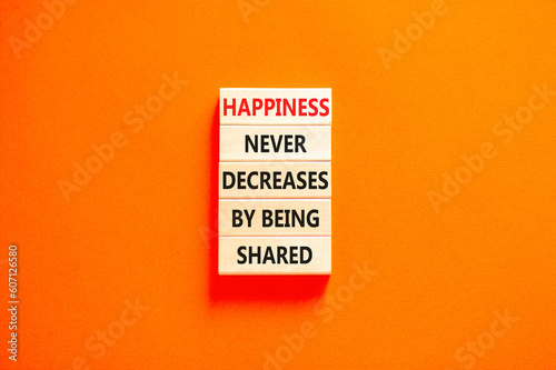 Happiness symbol. Concept words Happiness never decreases by being shared on wooden block. Beautiful orange table orange background. Motivational Happiness concept. Copy space.