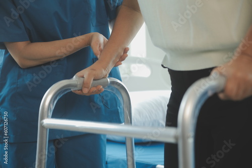 Physiotherapist assists her contented senior patient on folding walker. Recuperation for elderly, seniors care, nursing home.