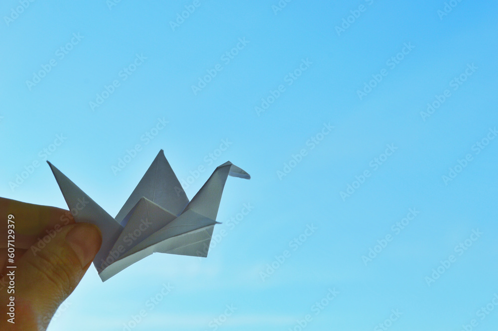 White paper origami bird on blue sky background. World Day of Peace. Day Against Humiliation. International Day Of Human Fraternity. International Day of Living Together in Peace White paper origami bird on blue sky background. World Day of Peace. Day Against Humiliation. International Day Of Human Fraternity. International Day of Living Together in Peace