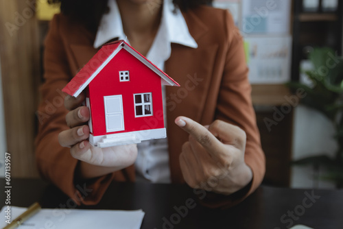 African American businesswoman with house model, Real estate agent and customer discussing for contract to buy house, insurance or loan real estate concept. 